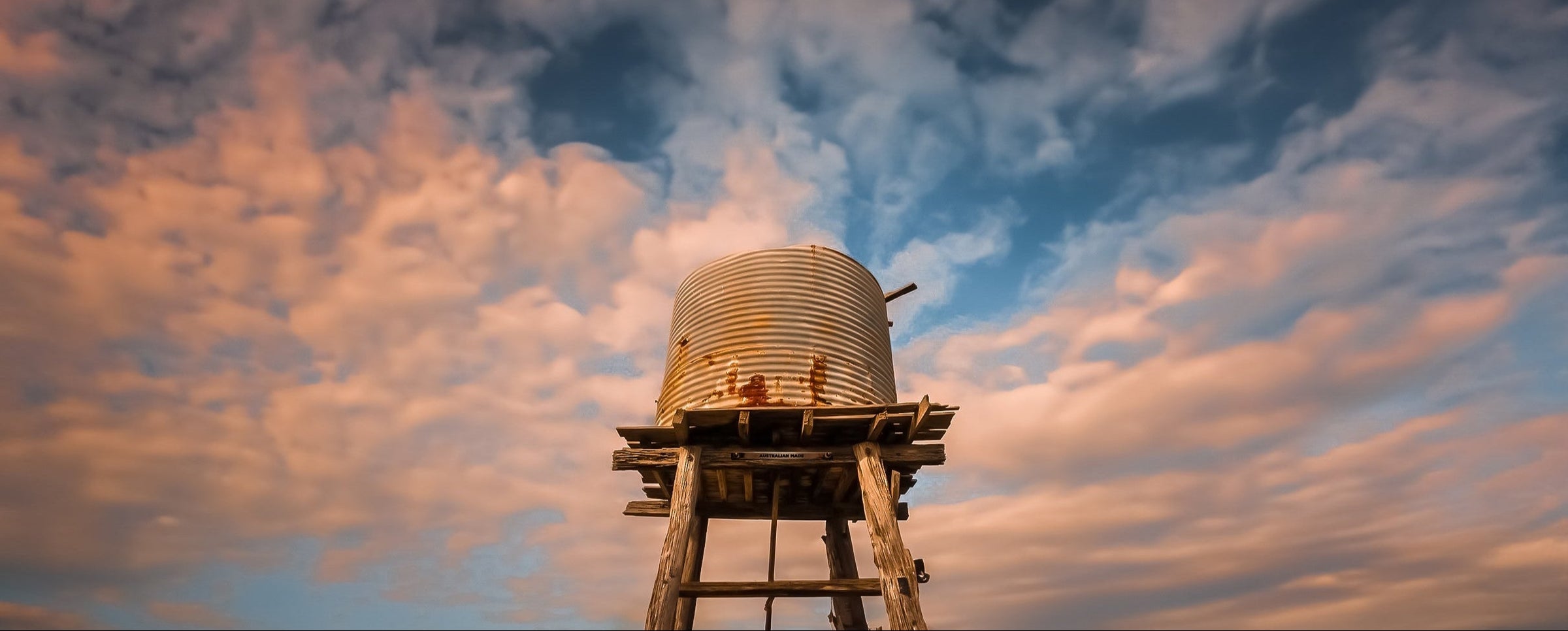 Water tower tank against a dramatic sky with clouds at sunset