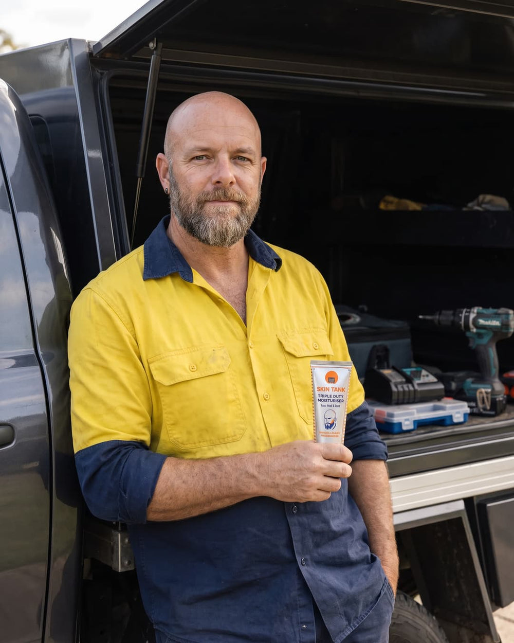 Skin Tank Triple Duty Moisturiser held by Australian tradie — natural men's face, head and beard moisturiser