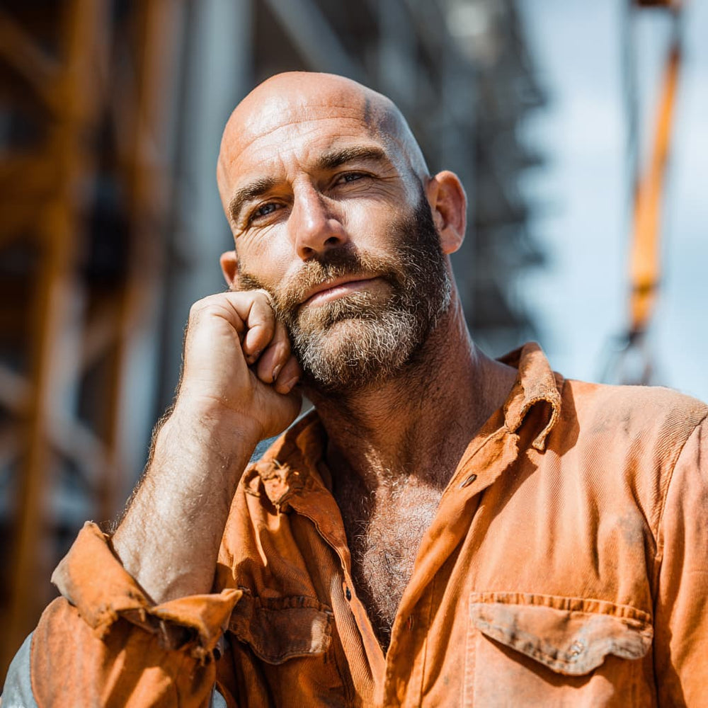 Bald bearded tradie on a worksite — Skin Tank Triple Duty Moisturiser fixes wind burn and dry skin for men who work outdoors